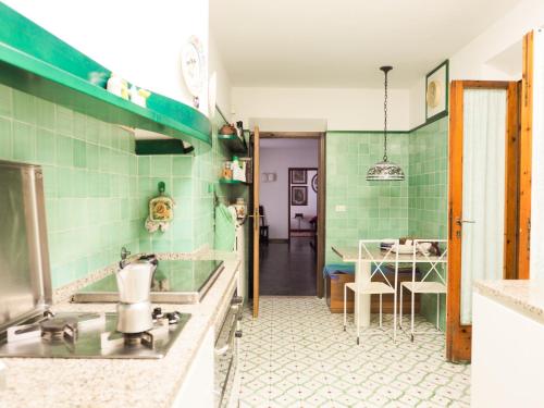 a kitchen with green tiled walls and a table at Villa LO SCHIOPPO vista mare in Marciana Marina