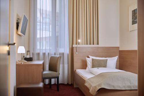 a bedroom with a bed and a desk and a chair at Hotel Prinzregent in Nürnberg