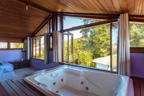 a large tub in a room with a large window at Caiowa Floripa guesthouse in Florianópolis