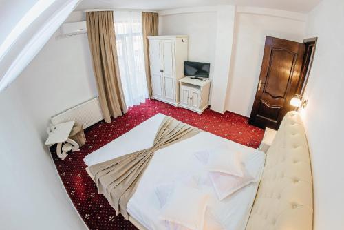 a bedroom with a white bed and a television at Pension Elegance in Gura Humorului