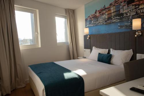 a hotel room with a bed and a desk and window at Hotel Porto Interface Trindade By Kavia in Porto