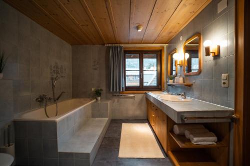 y baño con bañera, lavamanos y bañera. en D`Alpenapartments Bezau, en Bezau