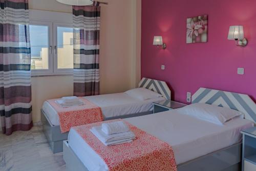 a hotel room with two beds and pink walls at Saint Trope Studios in Kalamaki Chanion
