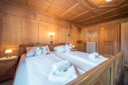 a bedroom with a large white bed with wooden walls at D`Alpenapartments Bezau in Bezau