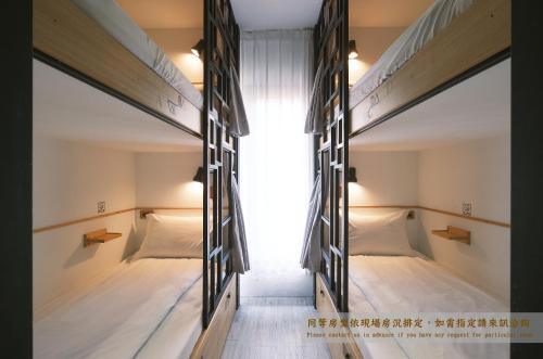 two bunk beds in a room with a window at Journey Hostel in Tainan