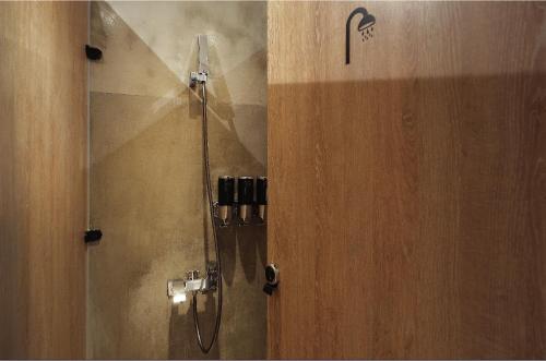 a shower in a bathroom with a wooden door at Journey Hostel in Tainan