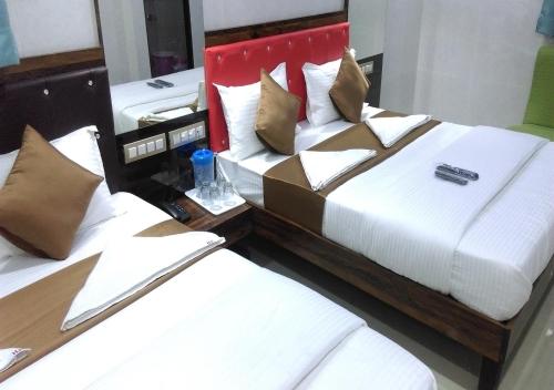 two beds in a hotel room with a mirror at Hotel Plaza- Near Byculla Railway Station in Mumbai