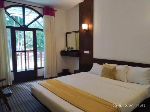 a bedroom with a large bed and a window at Ovitiyas Bandarawela in Bandarawela