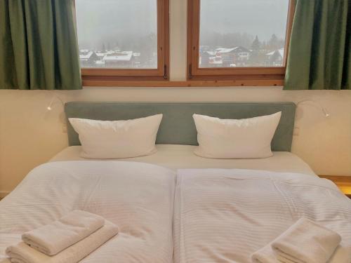 a bed with two towels on it with two windows at Feine FeWo im DG für 3 am Tegernsee in Bad Wiessee