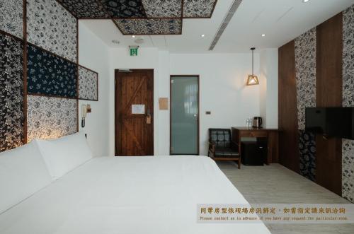 a bedroom with a large white bed and a desk at Journey Hostel in Tainan