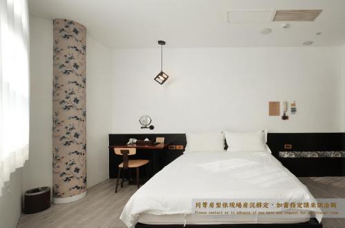 a bedroom with a white bed and a desk at Journey Hostel in Tainan