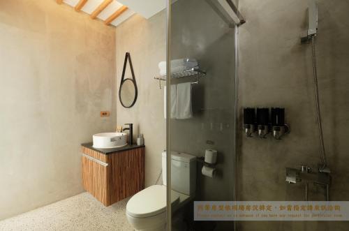a bathroom with a toilet and a glass shower at Journey Hostel in Tainan