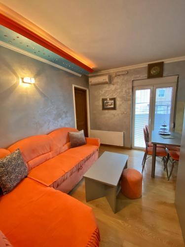 salon z pomarańczową kanapą i stołem w obiekcie Apartman Marko B w mieście Vrnjačka Banja