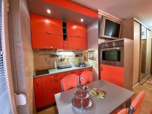 a small kitchen with red cabinets and a table at Apartman Marko B in Vrnjačka Banja