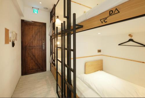 a room with a bunk bed and a wooden door at Journey Hostel in Tainan