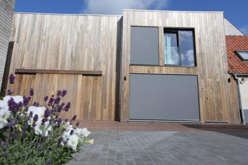 a wooden building with a large door with a large window at De Panne - Adinkerke - 't Voetbrugsje comfortabele nieuwbouw in De Panne