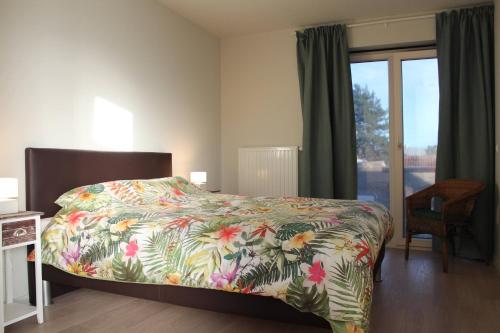 德帕內的住宿－De Panne - Adinkerke - 't Voetbrugsje comfortabele nieuwbouw，一间卧室配有一张带彩色床罩和窗户的床。