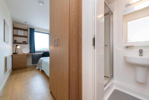 a bathroom with a sink and a bed in a room at For Students Only Private Bedroom with Shared Kitchen at Athena Hall in Ipswitch in Ipswich