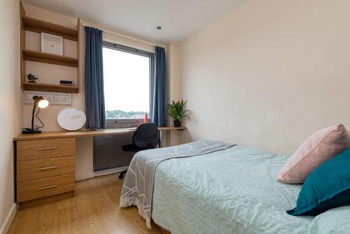 um quarto com uma cama, uma secretária e uma janela em For Students Only Private Bedroom with Shared Kitchen at Athena Hall in Ipswitch em Ipswich