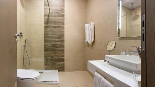 een badkamer met een wastafel, een toilet en een spiegel bij Hotel Kennedy Nova in Il-Gżira