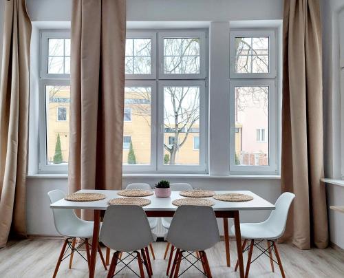 un tavolo bianco con sedie in una stanza con finestre di Agapella Apartamenty - Apartament Goyki 300 m from the beach a Sopot