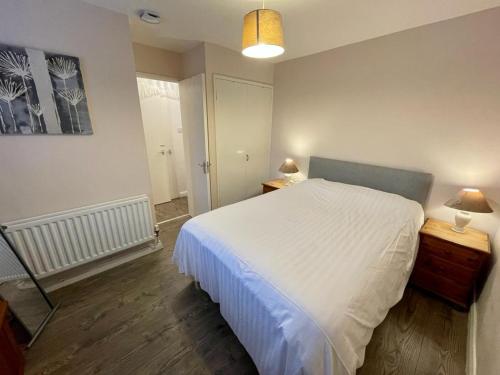 a bedroom with a large white bed and a mirror at Bishop's Gate Apartment in Derry Londonderry