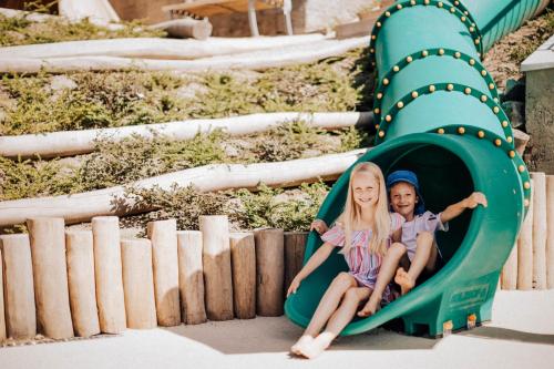 two children playing on a slide at a playground at Panoramahotel Am Sonnenhang in Tirolo