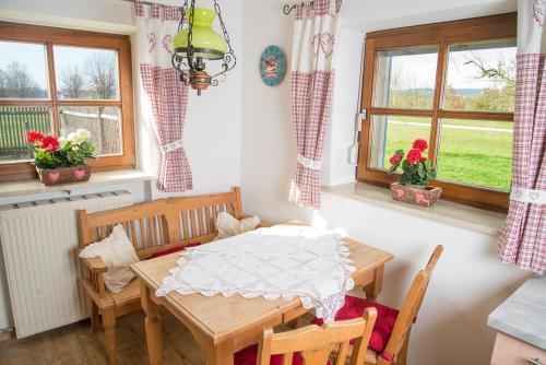 ein Esszimmer mit einem Tisch, Stühlen und Fenstern in der Unterkunft Ferienhaus Wolferstetter in Tittmoning