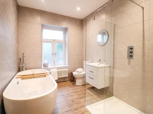 een badkamer met een bad, een douche en een toilet bij Cavendish Cottage in Matlock