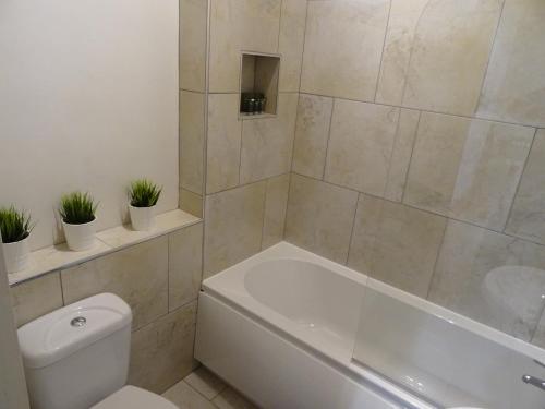 ein Badezimmer mit einer weißen Badewanne, einem WC und einem Waschbecken in der Unterkunft The Holmé in Leicester
