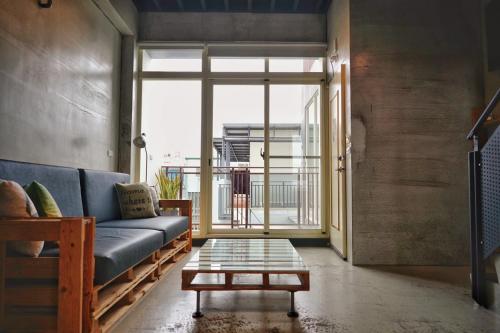 a living room with a blue couch and a large window at 40Inn Backpackers Warehouse in Taitung City