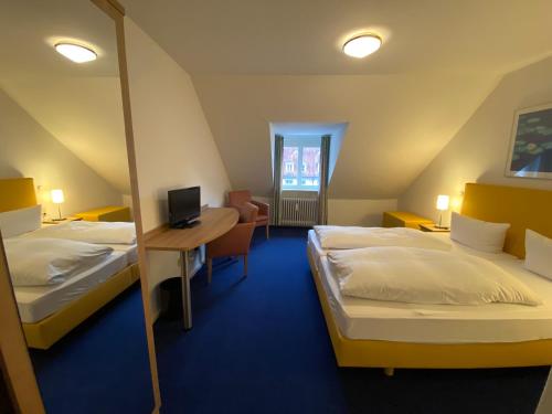 a room with two beds and a desk with a computer at Hotel am Kornmarkt in Heidelberg