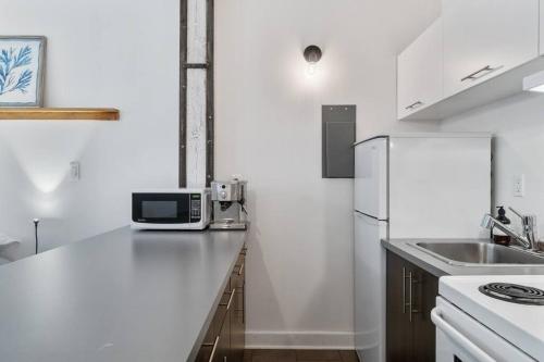 a white kitchen with a white refrigerator and a sink at INITIAL - MEMORY FACTORY - Centre-Ville de Québec in Quebec City
