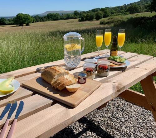 a wooden picnic table with bread and glasses of wine at Ribble Valley Retreat in Langho