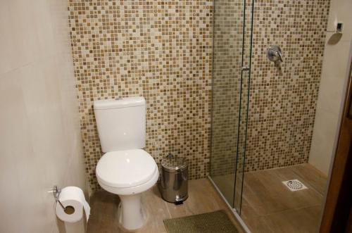 a bathroom with a toilet and a glass shower at Refúgio do Caracol Pipas e Chalés in Canela