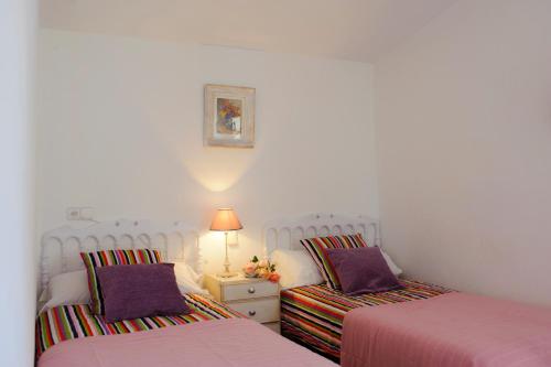 a bedroom with two beds and a night stand with a lamp at Finca Cavea in Caʼs Concos