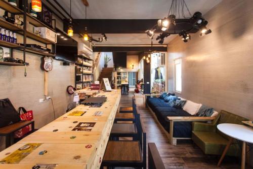 a bar with a long table and a couch in a room at 40Inn Backpackers Warehouse in Taitung City