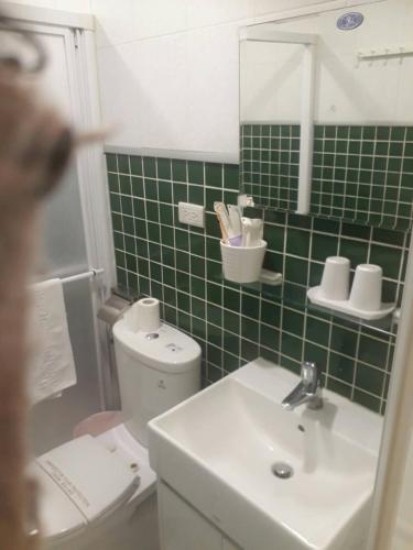 a bathroom with a sink and a toilet and green tiles at Water Source Coffee Homestay in Beigang