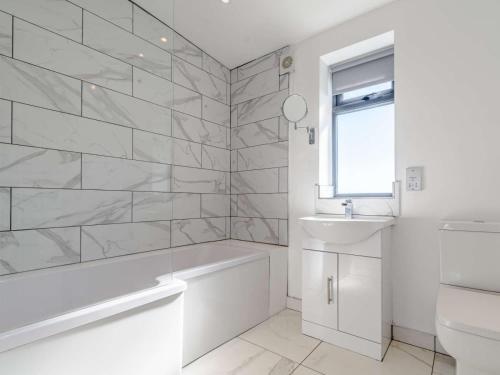 La salle de bains blanche est pourvue d'une baignoire et d'un lavabo. dans l'établissement 2-Bed Modern Bungalow - Outstanding Country Views, à Harrogate