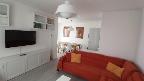 ein Wohnzimmer mit einem roten Sofa und einem TV in der Unterkunft Oasi di Pace e Tranquillità in Zelbio