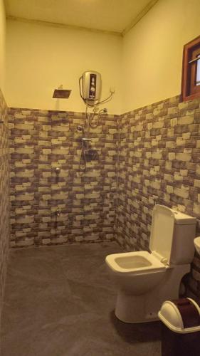 a bathroom with a toilet and a stone wall at Monara Backpacker Inn Unawatuna in Unawatuna