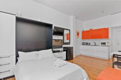 1 dormitorio blanco con 1 cama grande y cocina en INITIAL - ORANGE studio - Centre-Ville de Québec, en Quebec