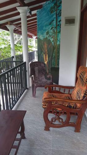 a porch with two chairs and a painting on the wall at Monara Backpacker Inn Unawatuna in Unawatuna