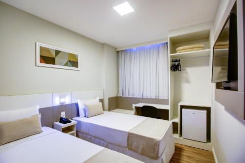 a hotel room with two beds and a television at Transamerica Fit Lafaiete in Conselheiro Lafaiete