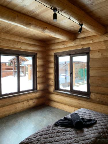 a bedroom with wooden walls and windows in a log cabin at 4REST ZRUB in Tukhlya