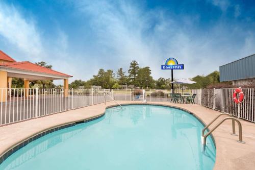 a swimming pool with a fence and a hotel sign at Days Inn by Wyndham Barnwell in Barnwell