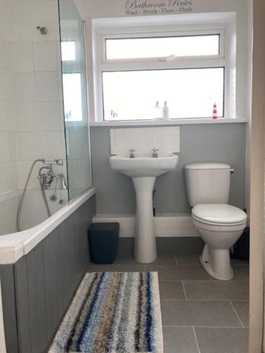 a bathroom with a toilet and a sink and a tub at Gulliver's Cottage in Frinton-On-Sea in Frinton-on-Sea