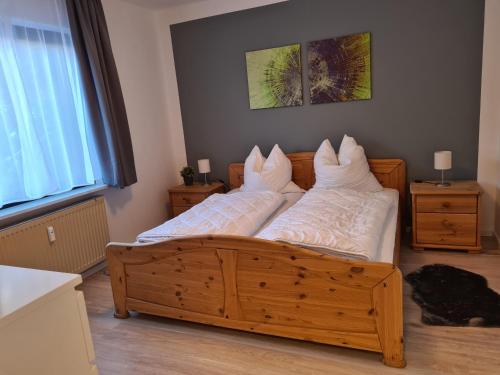 sypialnia z drewnianym łóżkiem z białymi poduszkami w obiekcie Ferienwohnungen Dora und Hansi w mieście Braunlage