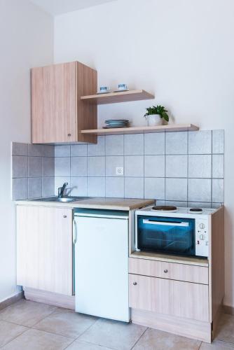 a kitchen with a white refrigerator and a microwave at Ilios Malia Hotel Resort in Malia
