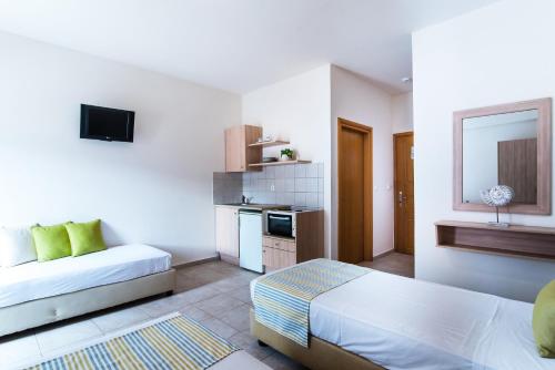 a white room with a bed and a couch in it at Ilios Malia Hotel Resort in Malia